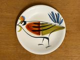 a plate with a bird painted on it on a wooden table