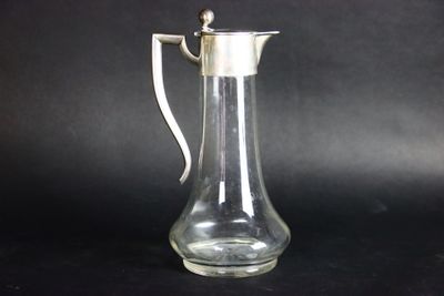 un pichet en verre muni d'une anse, sur fond noir