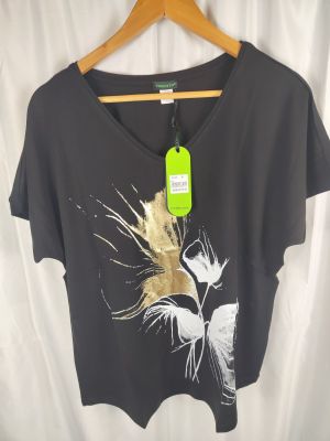 Le t-shirt est noir et orné d'une fleur dorée.