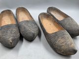 trois paires de vieilles chaussures en bois posées sur une surface blanche