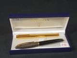 un stylo plume et un stylo à bille dans un coffret cadeau posé sur un fond noir
