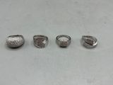 quatre bagues en argent sur une surface blanche, sur fond blanc