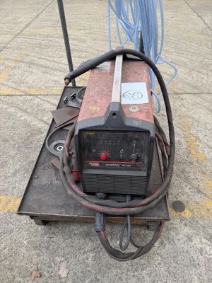 a welding machine sitting on a cart in a parking lot