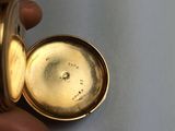 a person holding a gold pocket watch in their hand
