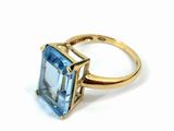 an image of a gold ring with a blue topaz stone