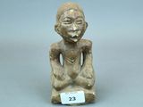 un gros plan sur une petite statue représentant une personne assise sur une table
