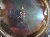 someone is holding a silver plate with a small design on it