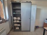 une grande armoire placée dans un coin de la pièce, sur laquelle s'entassent de nombreux papiers