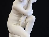 a white statue of a man sitting on a white pedestal