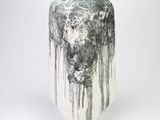 une photo en noir et blanc d'un vase posé sur une surface blanche
