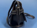 a small black purse with a leather strap on a blue background