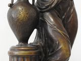 bronze statue of a woman with a vase on a pedestal