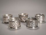 quatre serviettes en argent ornées de motifs, posées sur une table