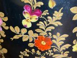 a black vase with gold and red flowers on it