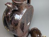 a brown vase and a small brown object on a table