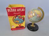 a small globe on a stand next to a box of books