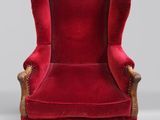 un fauteuil à oreilles en velours rouge, avec des pieds et des accoudoirs en bois