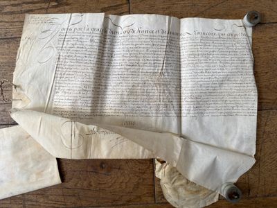 un vieux papier sur lequel il y a des inscriptions, posé sur un plancher en bois