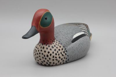 un petit canard en bois posé sur une table