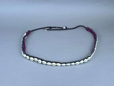 un gros plan d'un bracelet composé de coquillages blancs montés sur un cordon noir