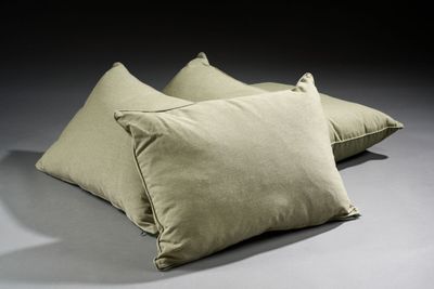 three pillows on a gray surface with a black background