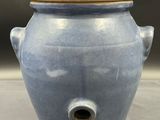 un vase bleu muni d'un couvercle, posé sur une table