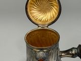 a silver pitcher with a gold lid on a table