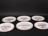 six white plates with black and white designs on them sitting on a black surface