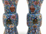 pair of blue vases with floral designs on them against a white background