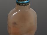 a small glass bottle with a red stone on top