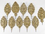 six sculptures murales en forme de feuille d'or sur un fond blanc