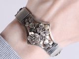 a woman wearing a silver bracelet with flowers on it