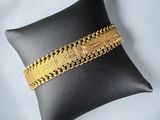 a black pillow with a gold bracelet on it