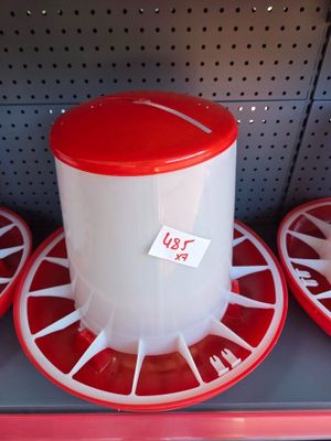three red and white bird feeders on display in a store