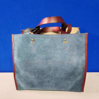un sac bleu muni d'une poignée en cuir, posé sur une table