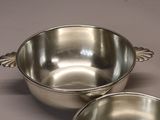 two silver bowls with handles on a table