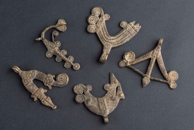 six figurines anciennes en bronze représentant des personnages et des animaux, sur un fond noir