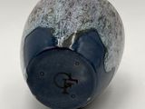 a close up of a blue vase on a white surface