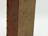 an old book with a brown cover sitting on top of a white surface