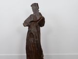 a sculpture of a woman in a long dress stands on a wooden floor