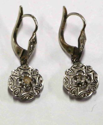 paire de boucles d'oreilles anciennes en argent, ornées d'un motif floral sur fond blanc