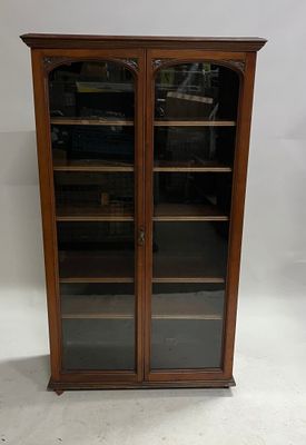 an antique wooden bookcase with glass doors and shelves