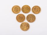 a group of five gold coins on a white surface