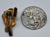 une broche en argent et une broche en or sur un fond blanc