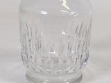 a clear glass vase with a handle on a white surface