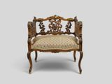 une chaise ancienne sculptée, dont l'assise est recouverte d'un tissu beige