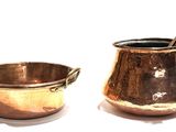 two pots and a spoon sitting next to each other