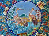 a close up of a decorative plate with birds and flowers on it