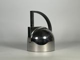 une théière en argent avec une poignée noire posée sur une table