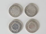 quatre types différents de pièces d'argent sur une surface blanche